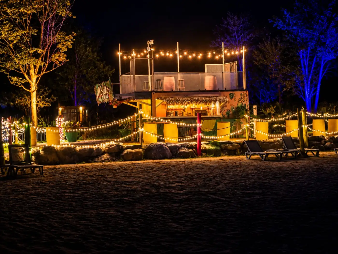Le bar extérieur et ses chaises longues sous les guirlandes lumineuses